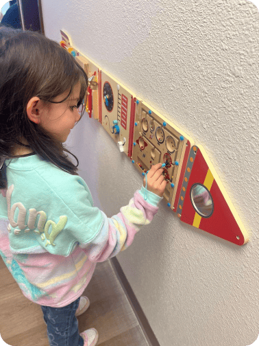 A girl is playing next to the wall